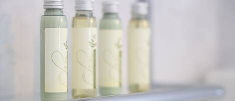 Four bottles of liquid on a white shelf.