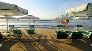 Una platja amb files de gandules verdes i ombrelles blanques, algunes amb adorns verds.