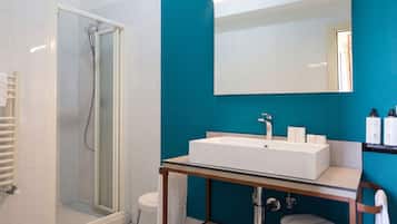 A modern bathroom with a glass-enclosed shower, a white sink with a mirror above, and a white toilet.