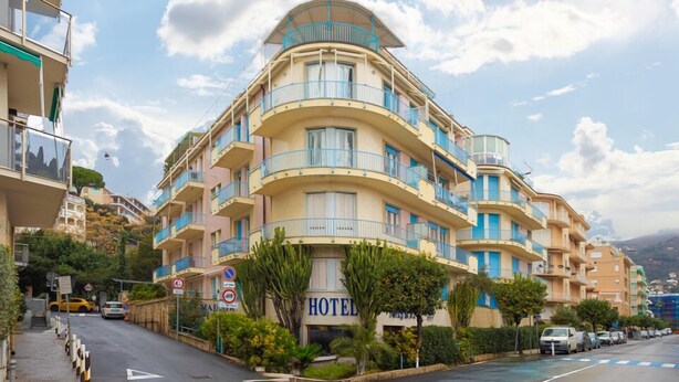 Un hotel de diverses plantes amb façana corba, balcons i un cartell que indica que és un hotel.