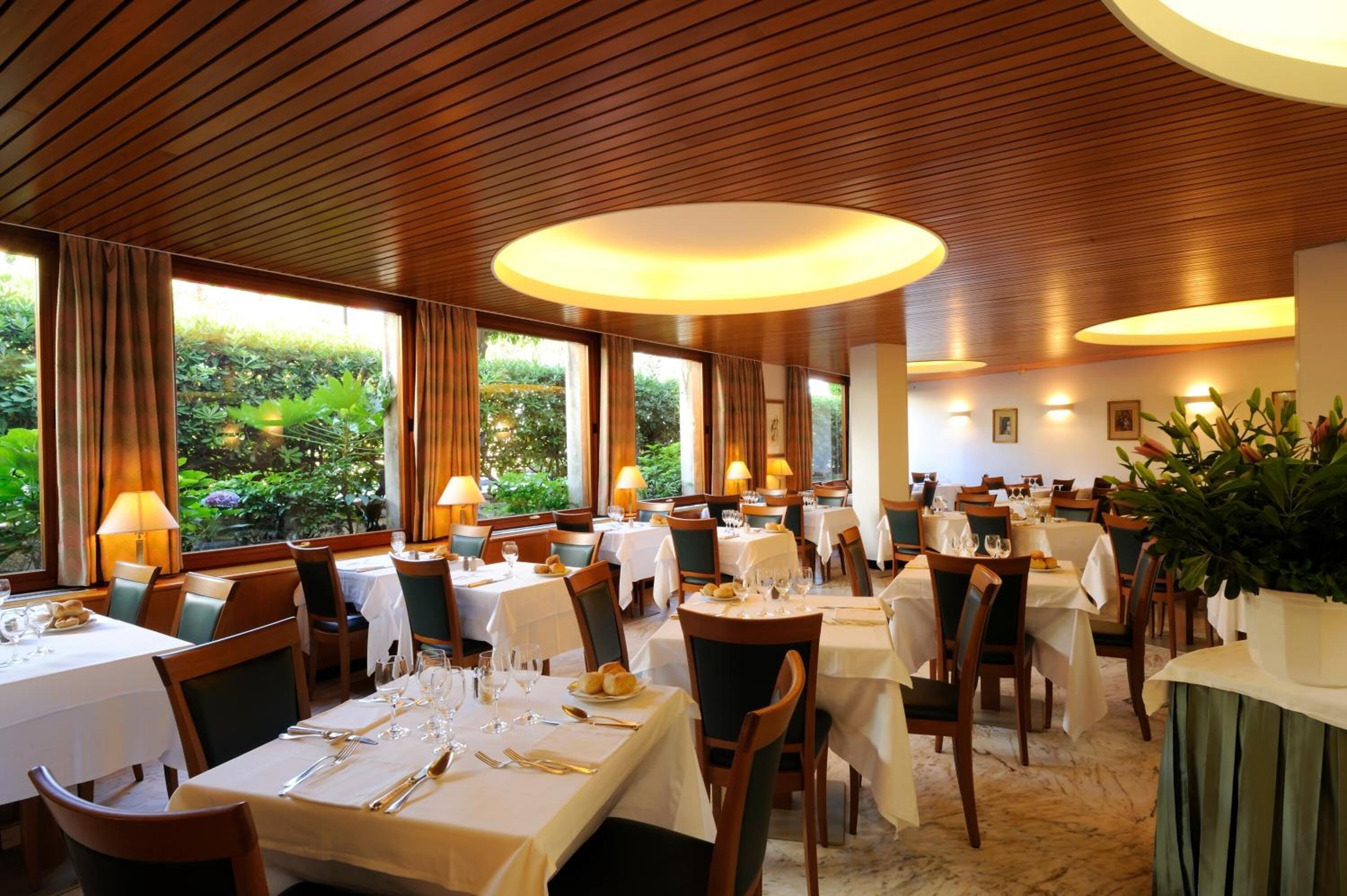 Ein Restaurant mit mehreren Tischen, jeder Tisch mit weißer Tischdecke, Kerzen und einer Auswahl an Gerichten gedeckt.