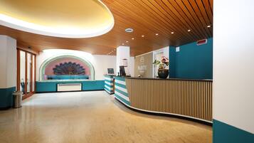 Un'accoglienza moderna con soffitto in legno, un bancone reception curvo e un'ampia decorazione a parete.
