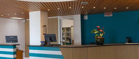 A reception area with a curved ceiling, a reception desk, a computer, and a potted plant.