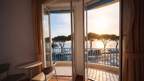 A balcony with a view of the sea and trees, a table, and a chair. - LVG Hotel Collection - Majestic (Alassio)