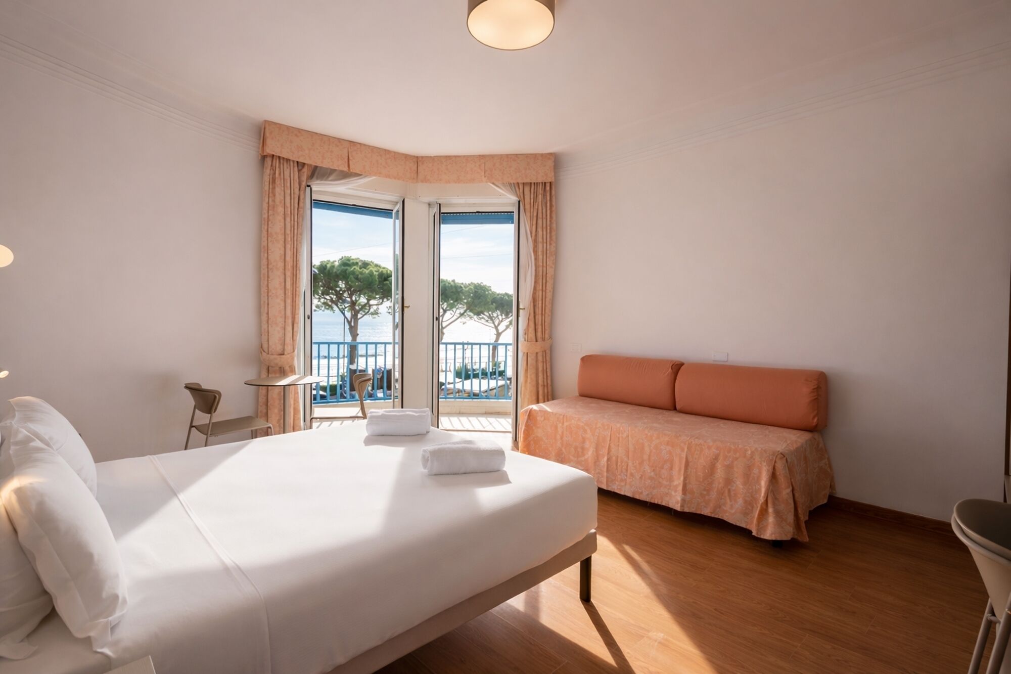 Ein Hotelzimmer mit Bett, Sitzecke, Meerblick und Balkon.