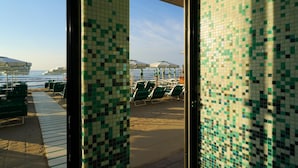A beachside view with tiled walls, sun loungers, and umbrellas. - LVG Hotel Collection - Majestic (Alassio)