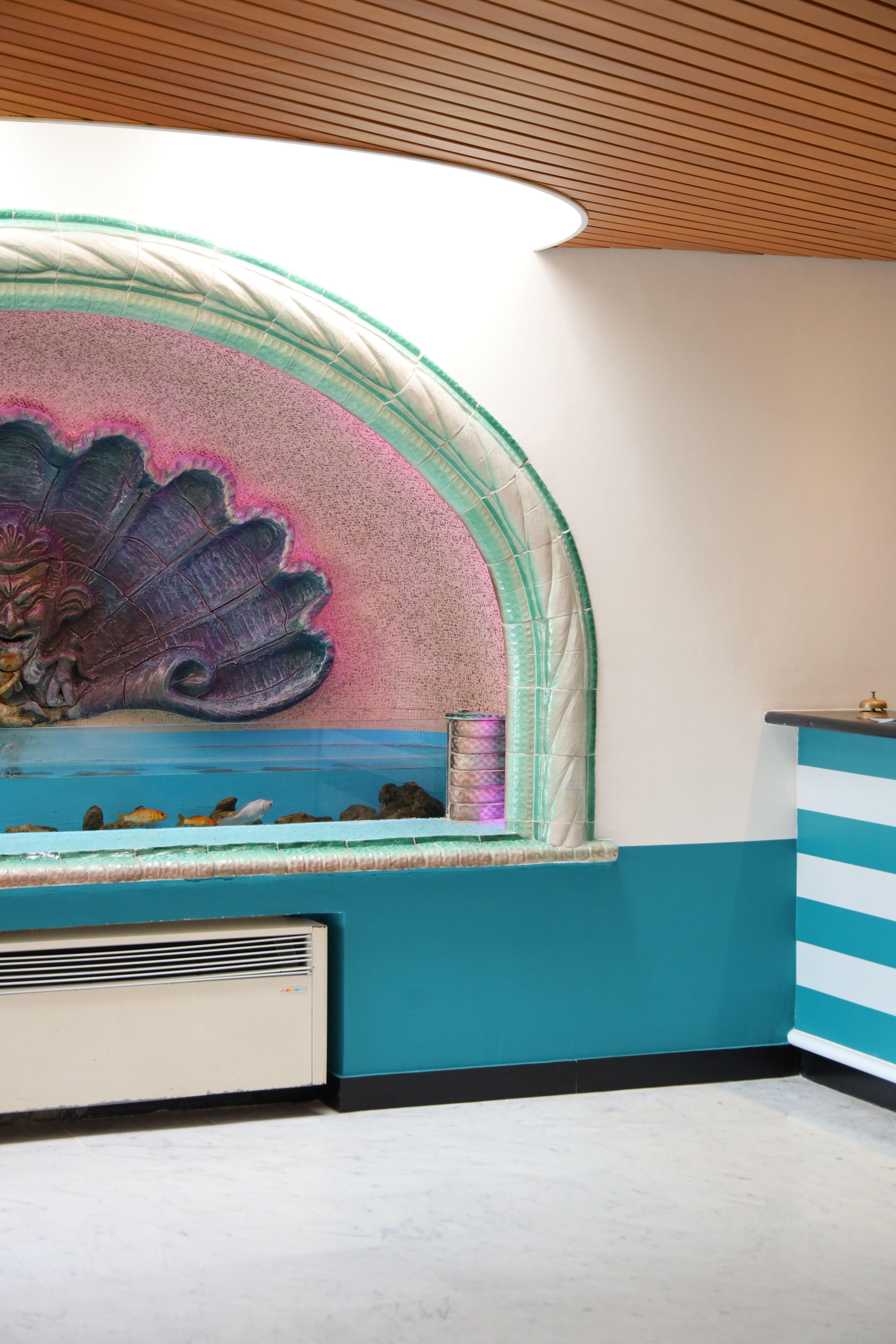 Una habitación con un acuario grande, un mueble a rayas y un techo de madera.