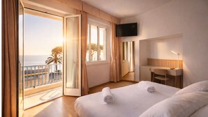 Habitació d'hotel amb balcó, un llit, escriptori i televisió.