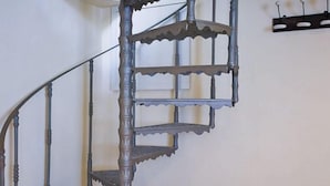 A spiral staircase with ornate metal railings and a wall-mounted light fixture. - Alfani Luxury Loft (Florence)