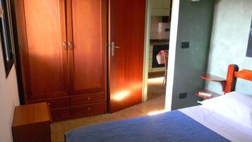 Une chambre à coucher avec un lit, une armoire en bois, une petite table et une chaise.
