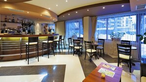 A modern hotel lobby with a curved reception desk, bar area, and seating arrangement. - Belmont (Bansko)