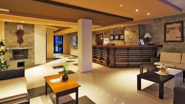 A modern lobby with a reception desk, seating area, and a fireplace. - Belmont (Bansko)