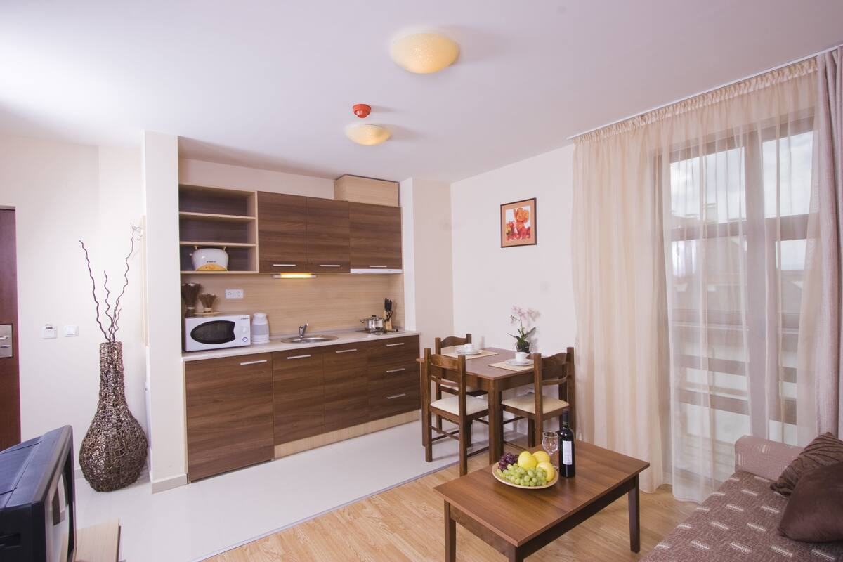 A modern kitchen with wooden cabinets, a microwave, and a dining area with a table and chairs.