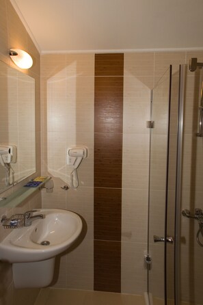 A bathroom with a sink, two hair dryers, a glass shower enclosure, and a mirror. - Belmont (Bansko)