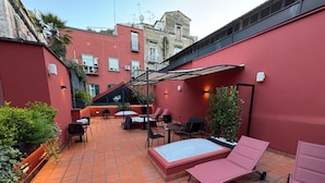 Eine Dachterrasse mit Fliesenboden, Sitzmöglichkeiten im Freien und Kübelpflanzen.