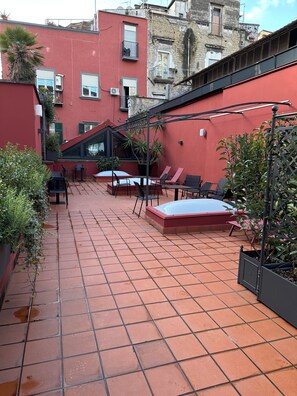 A courtyard with tiled flooring, outdoor seating, and potted plants. - Caruso Place Boutique & Wellness Suites (Naples)