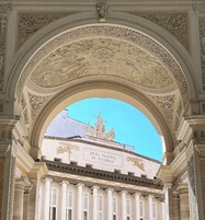 An ornate architectural archway with a clear view of a building labeled "Real Teatro Di S. Carlo" below.