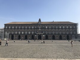 Un grande edificio storico con diverse arcate e una torre campanaria centrale.