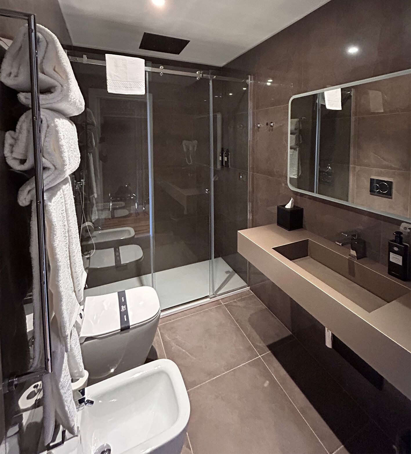 A modern bathroom with a glass-enclosed shower, a white sink, and a large mirror.