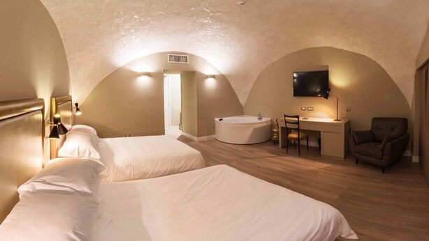 Ein Hotelzimmer mit zwei Betten, einem Schreibtisch, einem Stuhl, einem Fernseher und einer Badewanne.