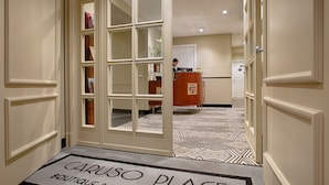 Ein Hotel Eingang mit Fußmatte, auf der 'CARUSO PLACE BOUTIQUE & WELLNESS SUITES' steht.
