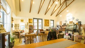 A cozy restaurant with wooden beams, a long wooden table, and various chairs. - Kismet Cottage (Pyeongchang)