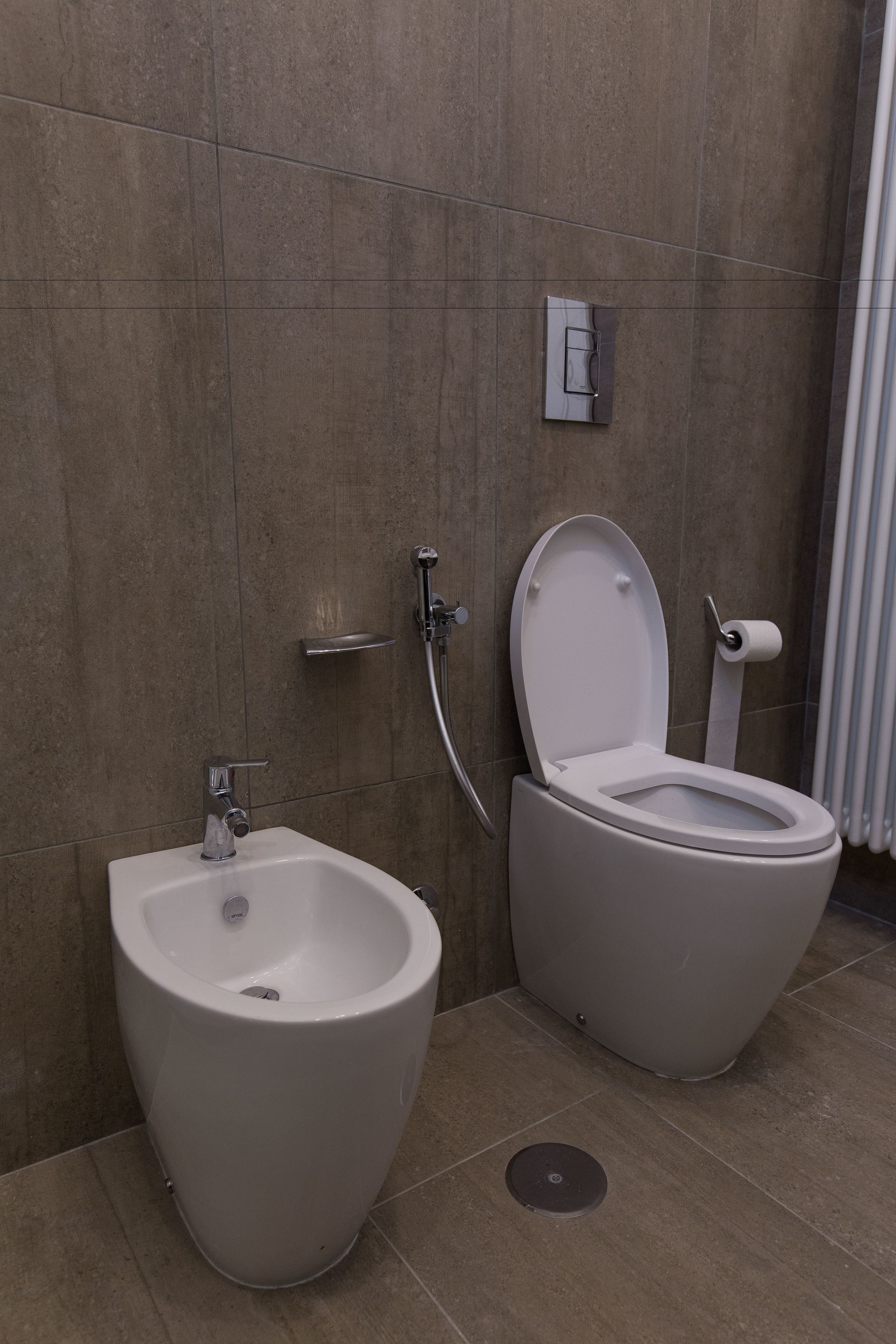 A modern bathroom with a bidet, a toilet, and a shower.
