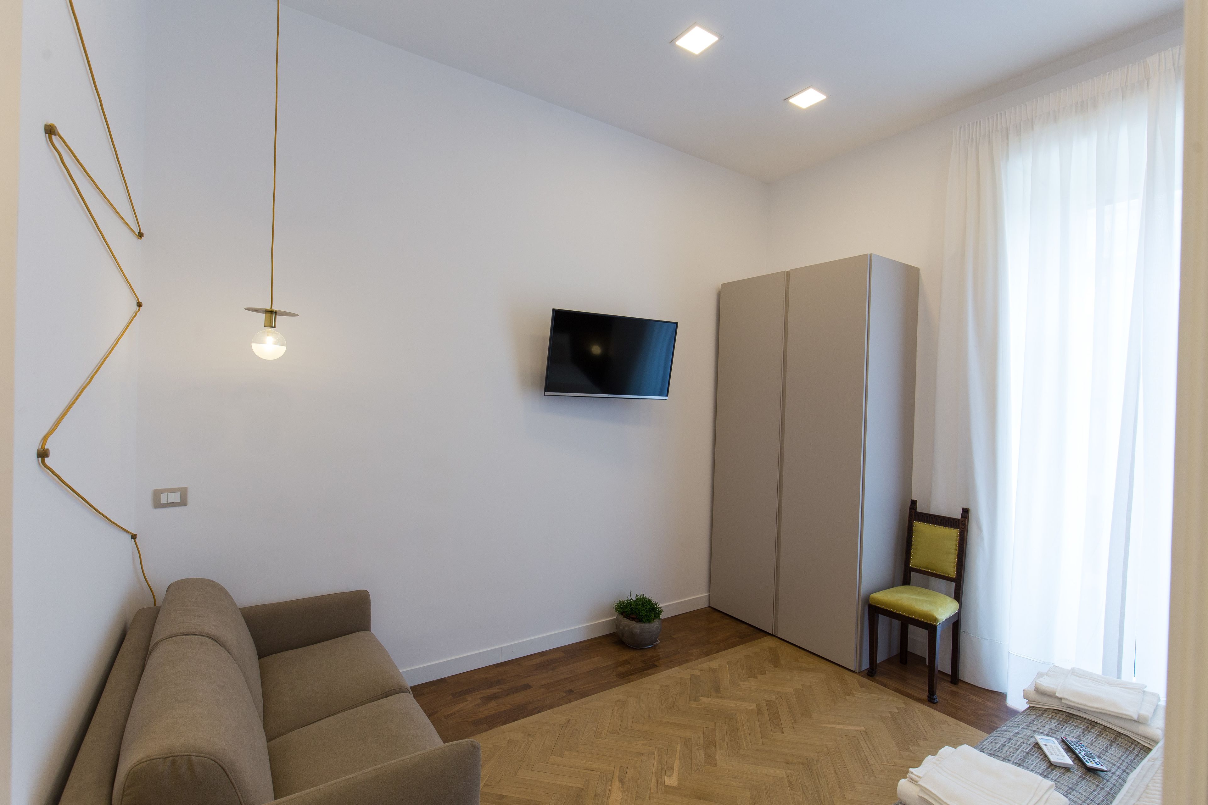 Una sala de estar moderna con un sofá, un televisor instalado en la pared, un sillón y una pequeña mesa con un control remoto.