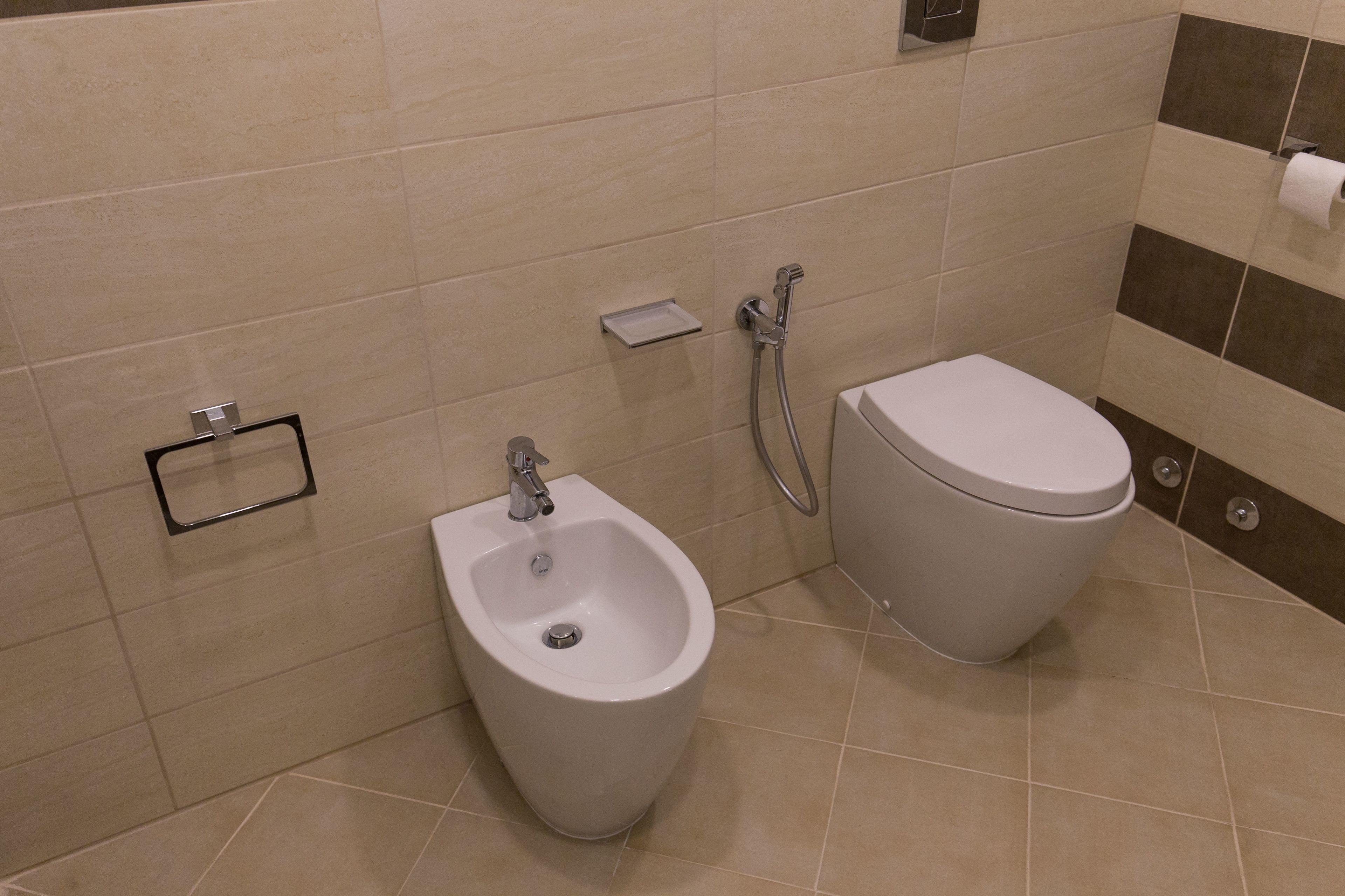 Un baño con bidé, inodoro y un perchero para toallas.