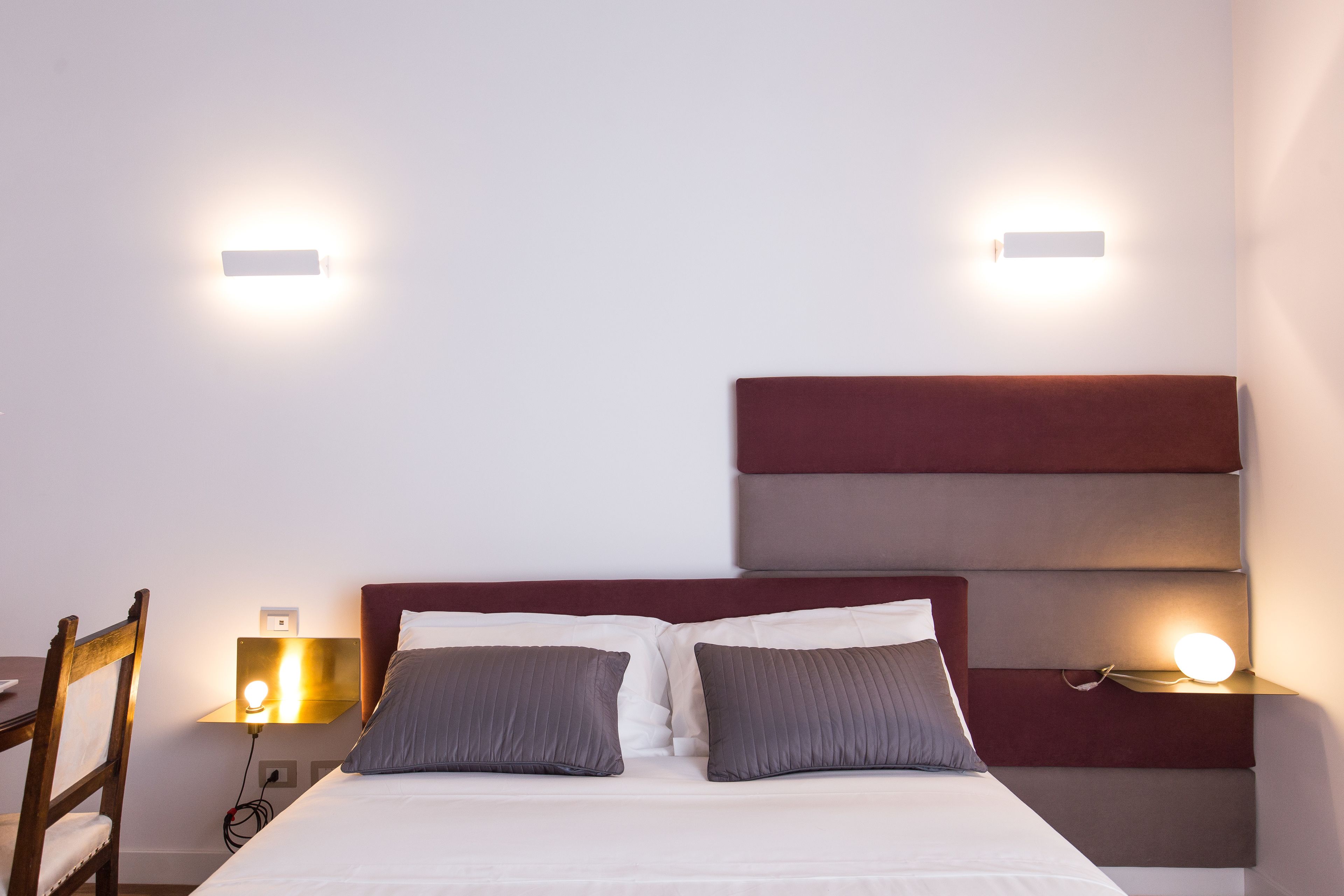 Een hotelkamer met een bed, twee nachtkastjes en een stoel.