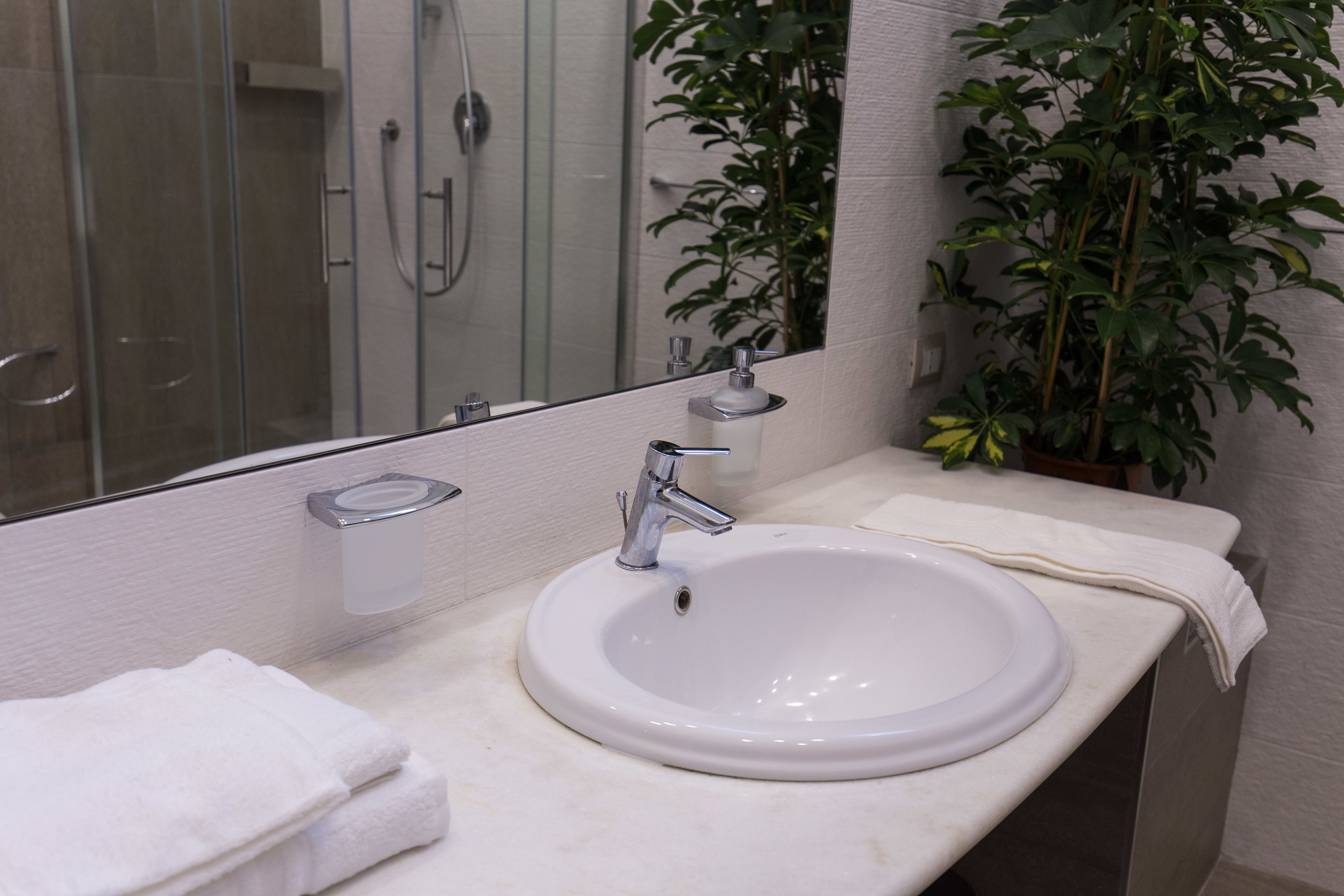 A bathroom with a white sink, a mirror, and a shower.