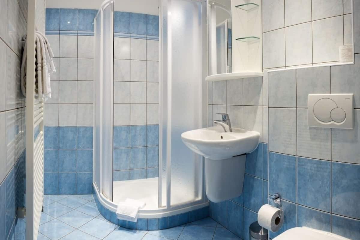 A bathroom with a shower, sink, toilet, and towel rack.