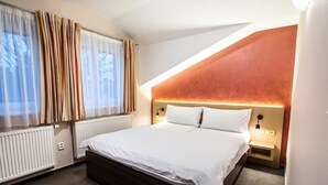 A modern hotel room with a large bed, a sloped ceiling, and a view of the outdoors. - Pension Bed & Breakfast (Kutna Hora)