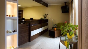 A modern living room with a wooden reception desk, a glass coffee table, and a potted plant. - Pension Bed & Breakfast (Kutna Hora)