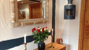 Une console en bois surmontée d’un vase contenant des roses rouges et blanches, de deux bougies et d’un miroir.