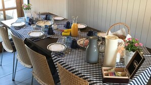 Un coin repas avec une nappe à carreaux, des chaises en osier, une horloge et un tableau encadré accroché au mur.