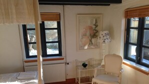 Une pièce comprenant un lit, une chaise, un radiateur, une fenêtre et un tableau.