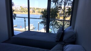 Ein Zimmer mit einem Bett und einem großen Fenster mit Blick auf ein Gewässer und angestellte Boote.