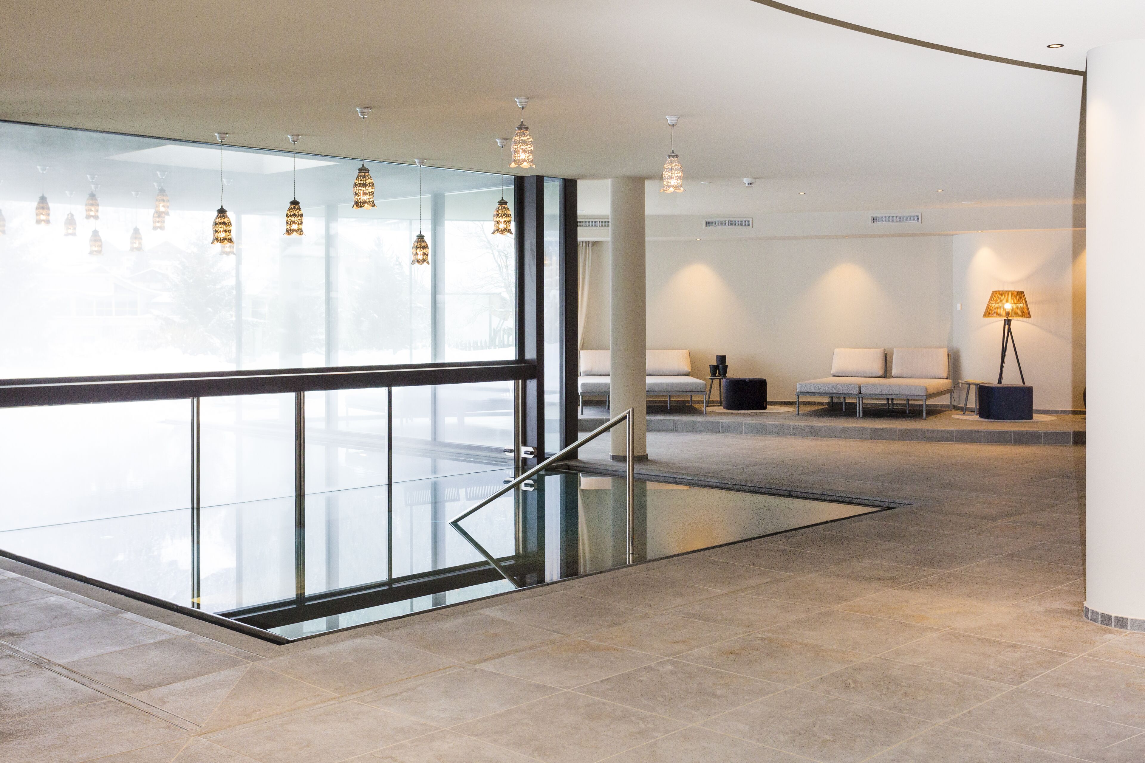 A spacious lobby with a glass floor, a staircase, and a seating area with a lamp.