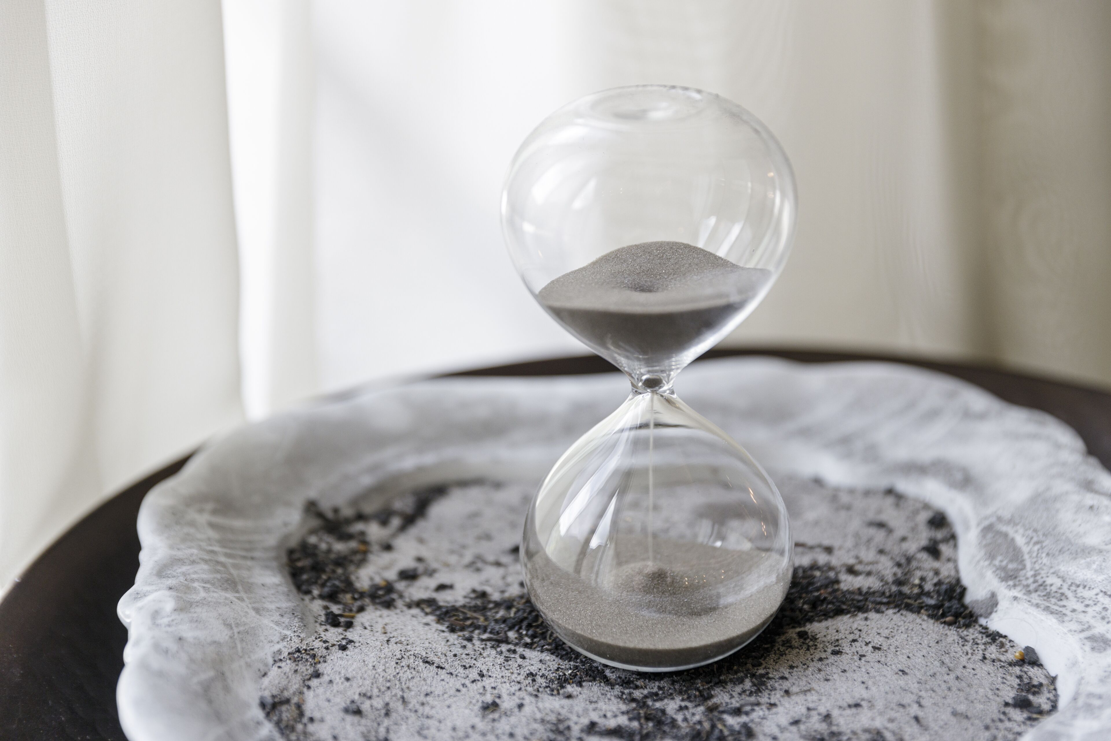 An hourglass on a textured white plate.