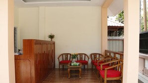 A covered outdoor seating area with wooden furniture and a tiled floor. - Ocean Ngapali Lodge (Ngapali)