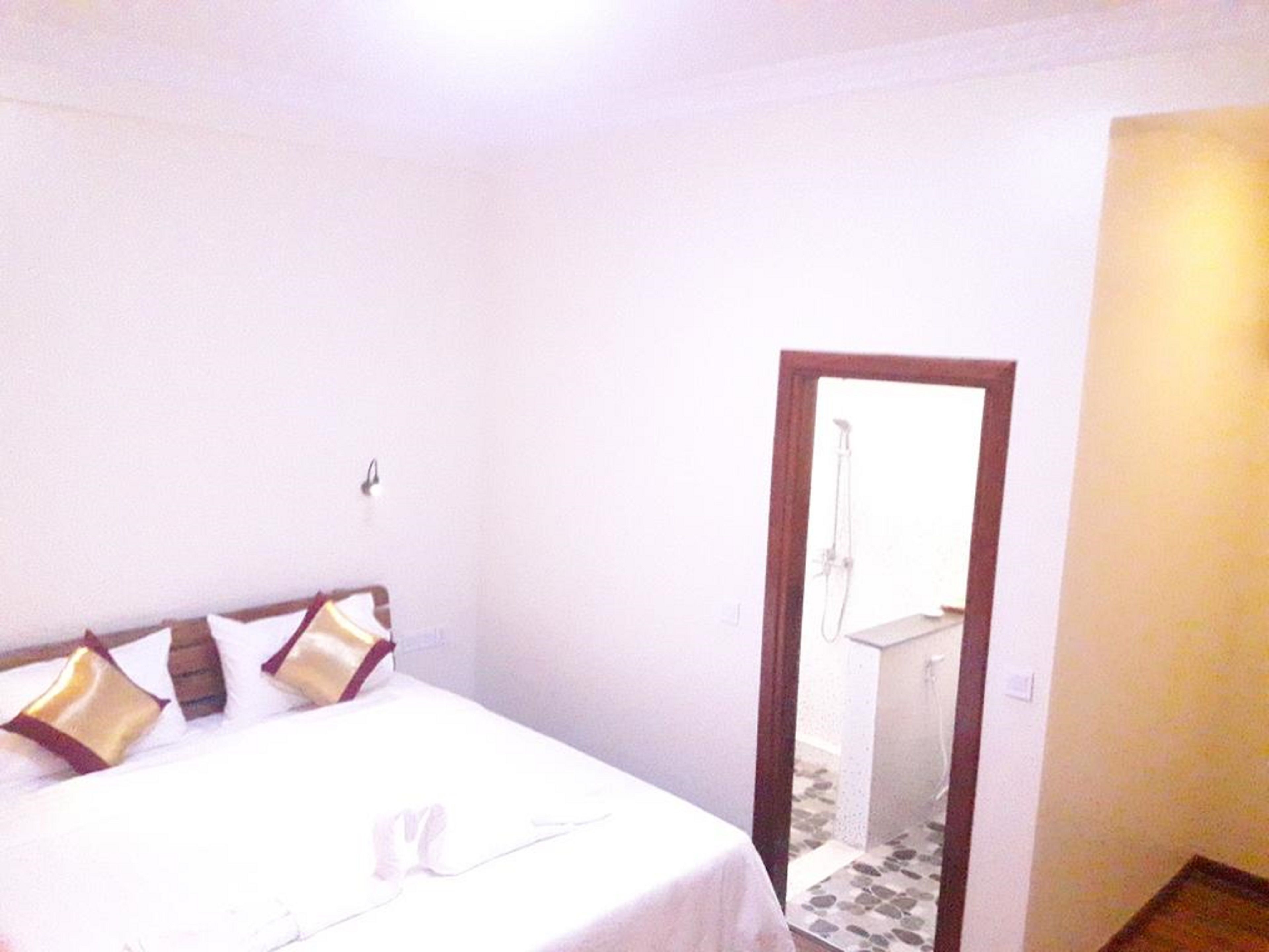 Une chambre à coucher avec un lit, un miroir et une porte donnant sur une salle de bain.