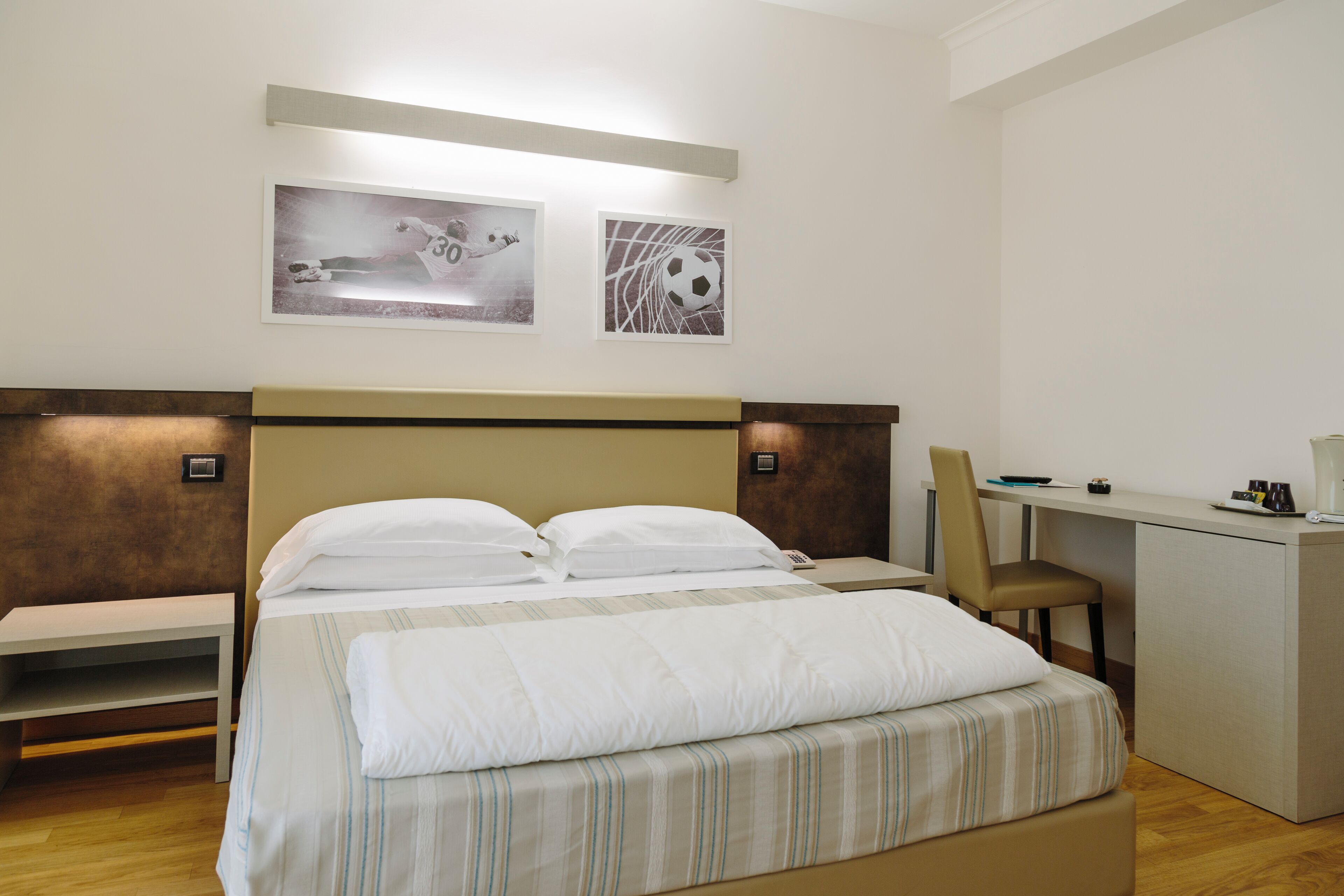 Una habitación de hotel con una cama, un escritorio y dos obras de arte colgadas en la pared.