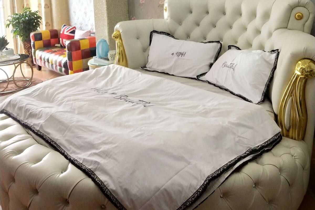 Ein Schlafzimmer mit einem gebügelten Kopfende, einem großen Bett mit weißen Leinen, einer Klimaanlage und blumigem Wandpapier.