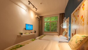 A hotel room with two beds, a TV on the wall, a window with curtains, and a shelf with small items.