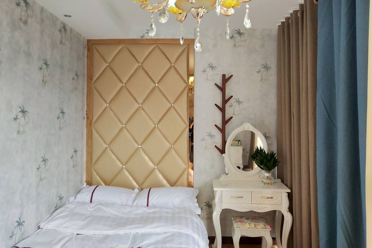 Ein Schlafzimmer mit einem Bett, einem Schminktisch mit Spiegel und einer Chandelüstere.