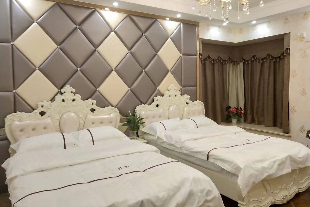 Ein Hotelzimmer mit zwei Betten, einem großen Spiegel, einer Kronleuchter und einer dekorativen Kopfteil.