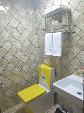 Une salle de bain équipée d’un lavabo, d’un porte-serviettes et d’un petit tabouret.