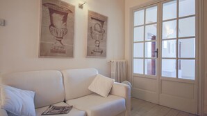 Ein Wohnzimmer mit einem weißen Sofa, zwei Wandleuchten und einem großen Fenster mit Blick.