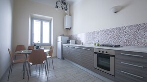 Eine moderne Küche mit Essbereich, ausgestattet mit Herd, Mikrowelle und einem Fenster mit Jalousien.